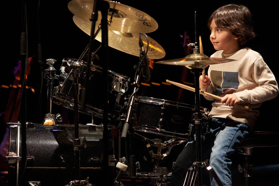 Criança a tocar bateria em palco, Recital de Natal 2024