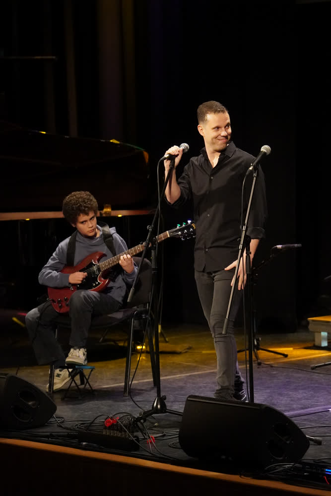 Professor a cantar ao microfone com aluno adolescente na guitarra elétrica, Recital de Primavera 2026