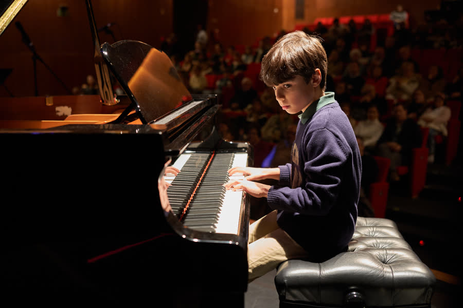Criança ao piano de cauda com a sala cheia atrás, Recital de Natal 2024